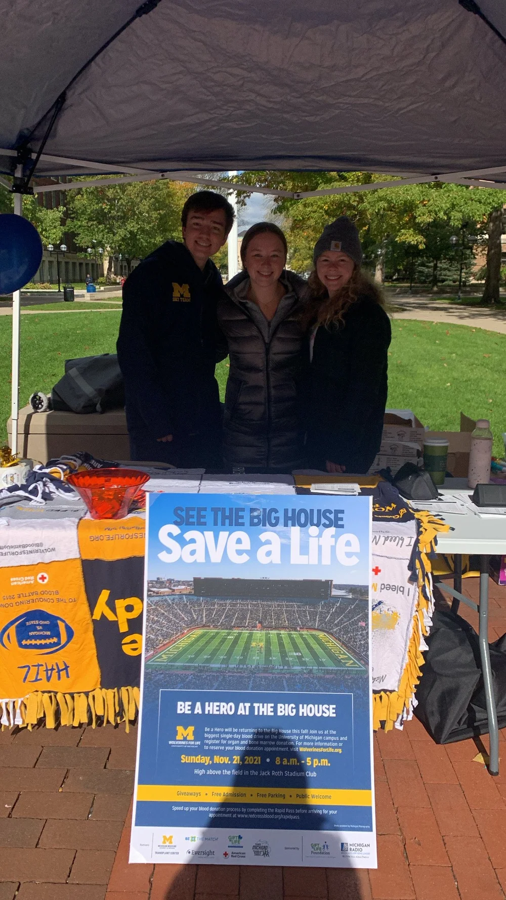 Three student volunteers at a Be a Hero information table