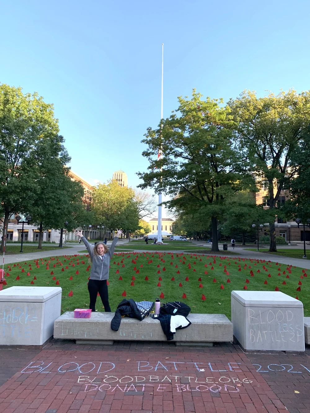 A BDU volunteer celebrating beside a field of blood drops on the Diag
