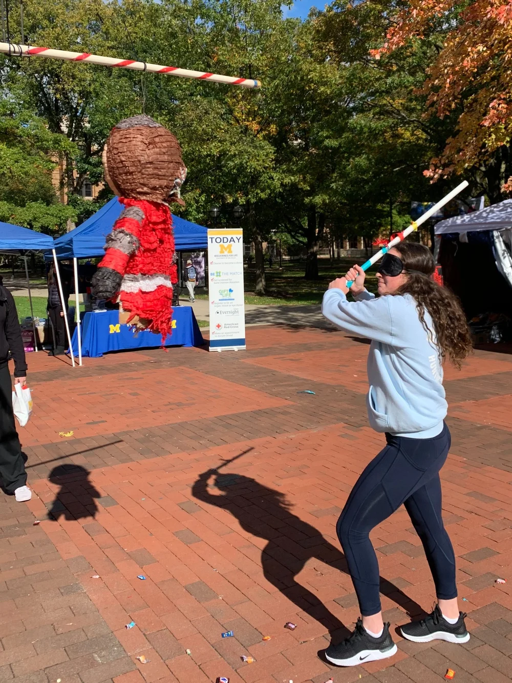 Student taking a swing at a rival mascot piñata during a campus event